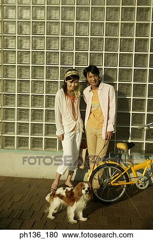 Stock Image - Young couple Leaning against a wall next to a bicycle. Fotosearch