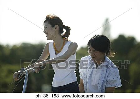 Stock Photo - Young couple Riding a bike. Fotosearch