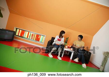 Stock Photo - Young couple sitting on a couch. Fotosearch