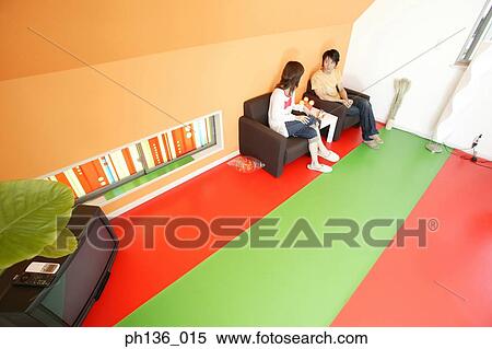 Young couple sitting on a couch View Large Photo Image Stock Photography - Young couple sitting on a couch. Fotosearch