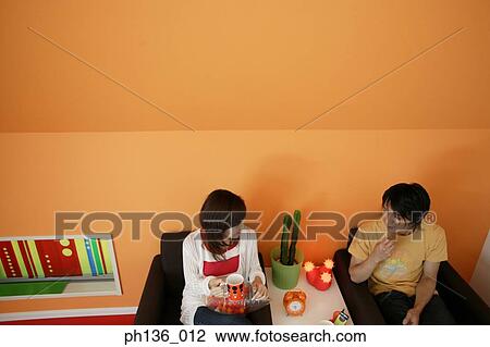 Young couple sitting on a couch talking View Large Photo Image Stock Image - Young couple sitting on a couch talking. Fotosearch