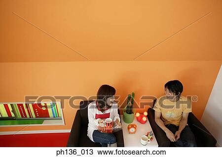 Stock Image - Young couple sitting on a couch talking. Fotosearch