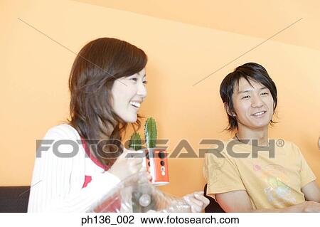 Young couple sitting together smiling View Large Photo Image Stock Image - Young couple sitting together smiling. Fotosearch