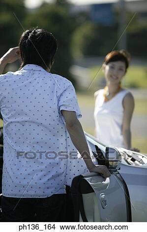 Picture - Young couple standing by a Car. Fotosearch