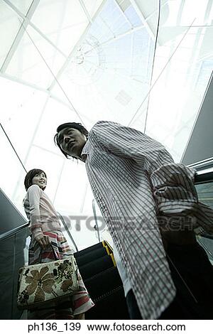 Stock Photo - Young couple standing on an escalator. Fotosearch