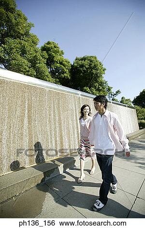 Stock Photograph - Young couple walking along a wall. Fotosearch