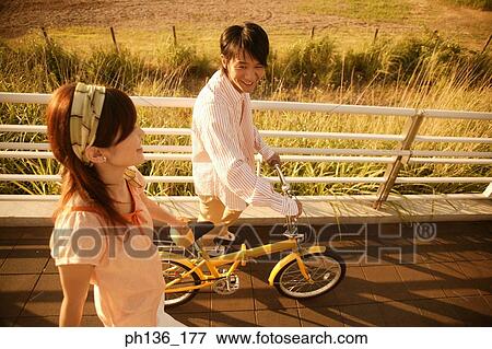 Stock Photo - Young couple walking with a bicycle. Fotosearch