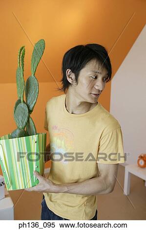Young man carrying a potted cactus plant View Large Photo Image Stock Photography - Young man carrying a potted cactus plant. Fotosearch