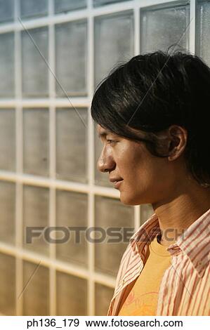 Stock Photo - Young man Leaning against a wall looking ahead. Fotosearch