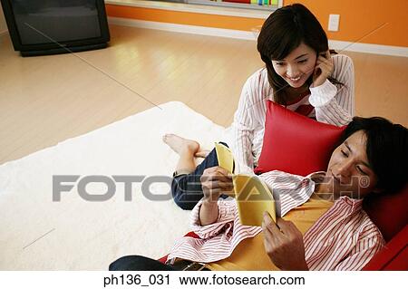 Young man lying on a couch and a woman sitting on floor View Large Photo Image Stock Image - Young man lying on a couch and a woman sitting on floor. Fotosearch
