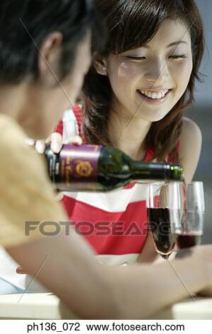 Young man pouring red wine into a woman's glass View Large Photo Image Stock Image - Young man pouring red wine into a woman's glass. Fotosearch