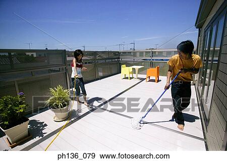 Young woman holding a hose while a man mops the floor View Large Photo Image Stock Photo - Young woman holding a hose while a man mops the floor. Fotosearch