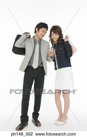 Stock Image - Businessman and a businesswoman listening to an MP3 player. Fotosearch