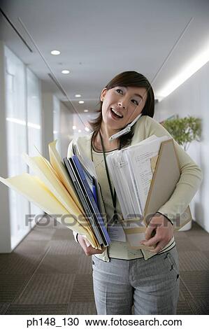 Businesswoman carrying files and using a mobile phone View Large Photo Image Stock Image - Businesswoman carrying files and using a mobile phone. Fotosearch