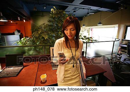 Businesswoman looking at a mobile phone View Large Photo Image Stock Photo - Businesswoman looking at a mobile phone. Fotosearch