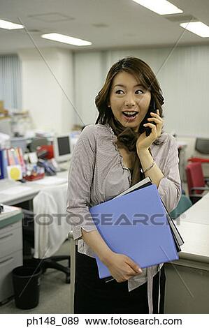 Businesswoman using a mobile phone and looking cheerful View Large Photo Image Stock Photo - Businesswoman using a mobile phone and looking cheerful. Fotosearch