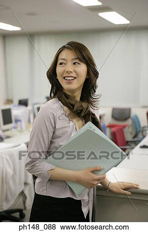 Close-up of a businesswoman holding a file and smiling View Large Photo Image Stock Photo - Close-up of a businesswoman holding a file and smiling. Fotosearch
