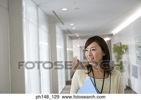Stock Photo - Close-up of a businesswoman holding a file and smiling. Fotosearch