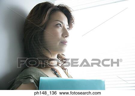 Close-up of a businesswoman holding a file and thinking View Large Photo Image Stock Photograph - Close-up of a businesswoman holding a file and thinking. Fotosearch