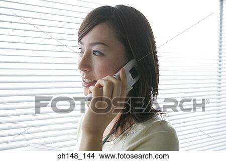 Picture - Close-up of a businesswoman using a mobile phone and smiling. Fotosearch