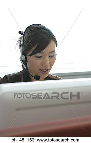 Close-up of a businesswoman wearing headset and using a computer View Large Photo Image Stock Image - Close-up of a businesswoman wearing headset and using a computer. Fotosearch