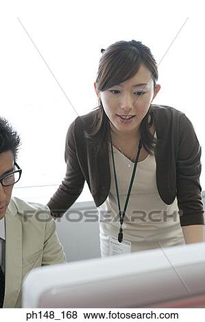 Stock Photo - Close-up of a businesswoman with a businessman using a computer. Fotosearch
