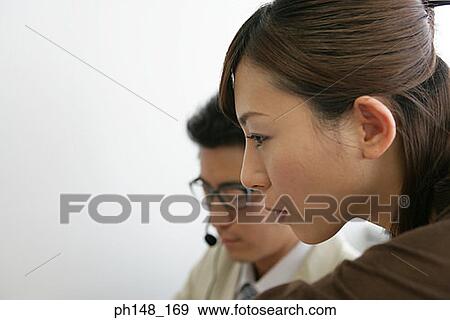 Close-up of a businesswoman with a businessman wearing headset View Large Photo Image Stock Photo - Close-up of a businesswoman with a businessman wearing headset. Fotosearch