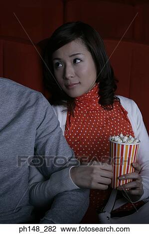 Stock Image - Close-up of a young couple sitting in a movie theater. Fotosearch