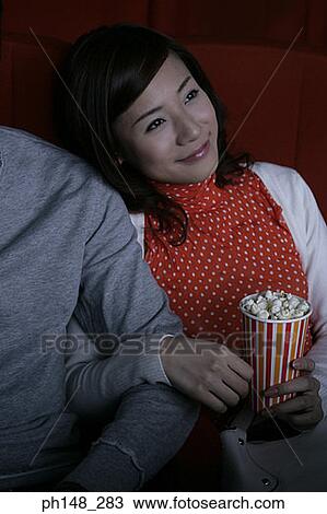 Stock Image - Close-up of a young couple sitting in a movie theater. Fotosearch