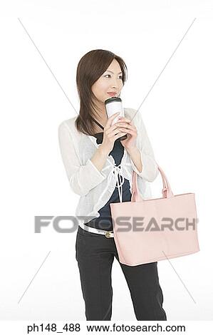 Close-up of a young woman holding a bottle and a purse View Large Photo Image Stock Photo - Close-up of a young woman holding a bottle and a purse. Fotosearch