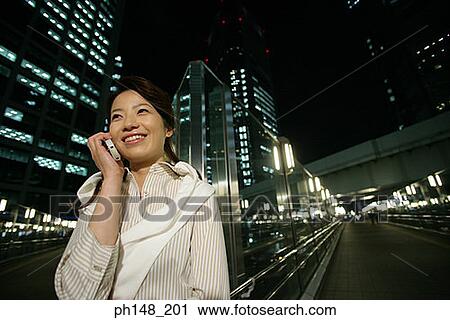 Stock Image - Close-up of a young woman talking on a mobile phone and smiling. Fotosearch