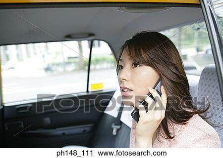 Stock Image - Close-up of a young woman using a mobile phone in a car. Fotosearch