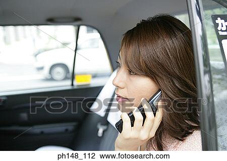 Close-up of a young woman using a mobile phone in a car View Large Photo Image Stock Image - Close-up of a young woman using a mobile phone in a car. Fotosearch