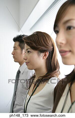 Stock Image - Close-up of business executives standing in a row and thinking. Fotosearch