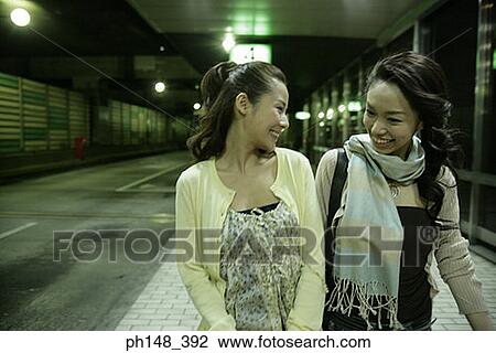 Stock Image - Close-up of two young women smiling at a subway station. Fotosearch