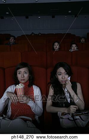 Close-up of two young women watching a movie in a movie theater View Large Photo Image Stock Image - Close-up of two young women watching a movie in a movie theater. Fotosearch