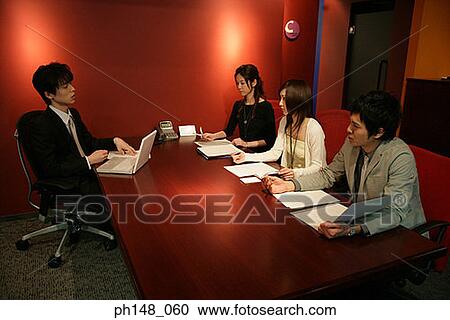 Stock Image - High angle view of two businessmen and two businesswomen in a meeting. Fotosearch