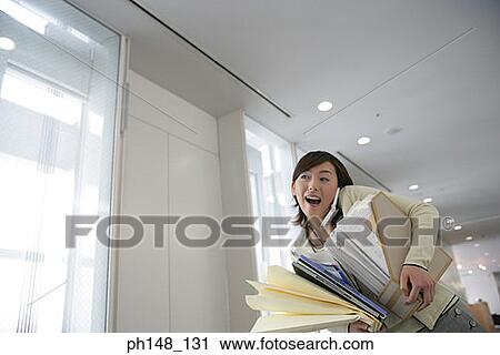Low angle view of a businesswoman using a mobile phone and carrying files in an office View Large Photo Image Stock Image - Low angle view of a businesswoman using a mobile phone and carrying files in an office. Fotosearch