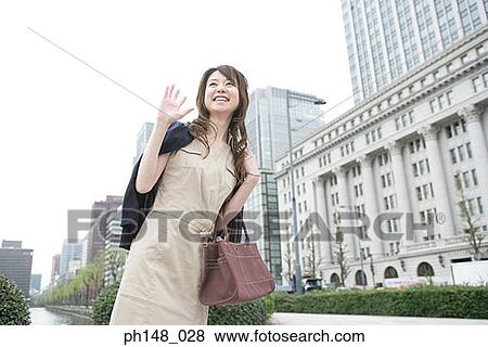 Low angle view of a young woman carrying a purse and smiling View Large Photo Image Stock Photo - Low angle view of a young woman carrying a purse and smiling. Fotosearch