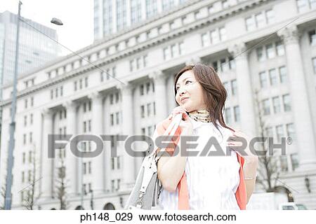 Stock Photo - Low angle view of a young woman carrying a purse. Fotosearch