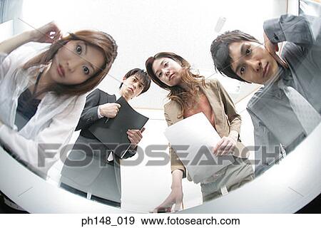 Stock Photo - Low angle view of two businessmen and two businesswomen in a conference room. Fotosearch