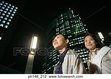 Stock Image - Low angle view of two young women smiling. Fotosearch