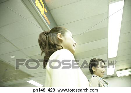 Stock Photo - Low angle view of two young women smiling together. Fotosearch