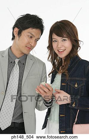 Portrait of a businessman and a businesswoman listening to an MP3 player View Large Photo Image Picture - Portrait of a businessman and a businesswoman listening to an MP3 player. Fotosearch