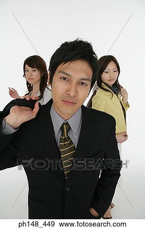 Stock Photo - Portrait of a businessman carrying a bag with two businesswomen in the background. Fotosearch