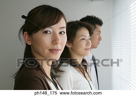 Portrait of a businesswoman standing with her colleagues and smiling View Large Photo Image Stock Photography - Portrait of a businesswoman standing with her colleagues and smiling. Fotosearch