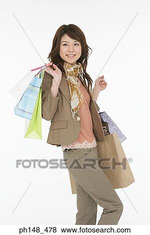Stock Photo - Portrait of a young woman carrying shopping bags. Fotosearch