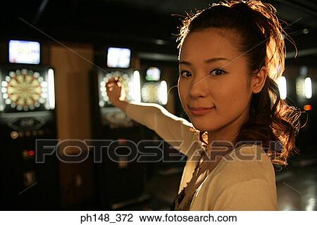 Portrait of a young woman holding a dart in a nightclub View Large Photo Image Stock Image - Portrait of a young woman holding a dart in a nightclub. Fotosearch