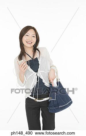 Stock Image - Portrait of a young woman listening to an MP3 player. Fotosearch