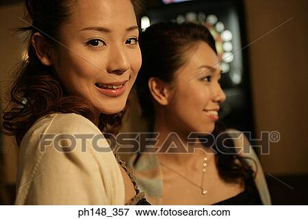 Stock Photo - Portrait of a young woman smiling together with her friend. Fotosearch